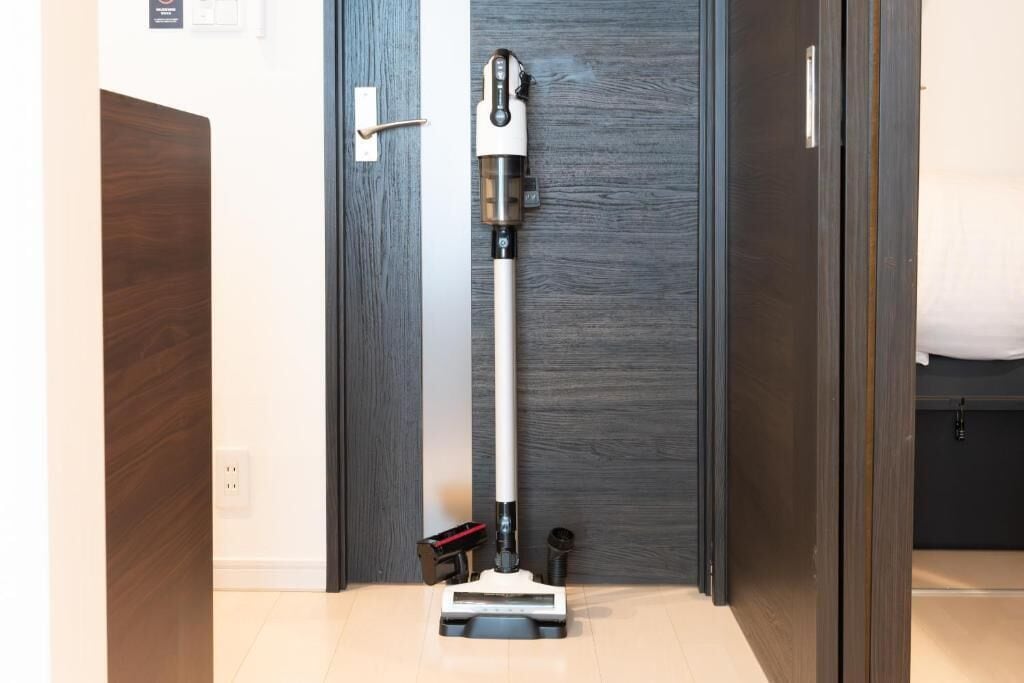 A vacuum cleaner in a hallway with a wooden door and a white wall.