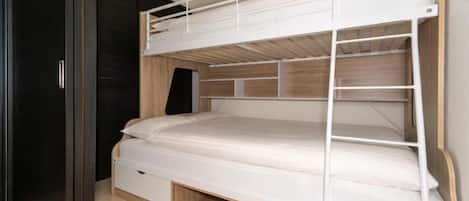 Una cama litera con estructura de madera y una cama inferior con cajones para guardar objetos.
