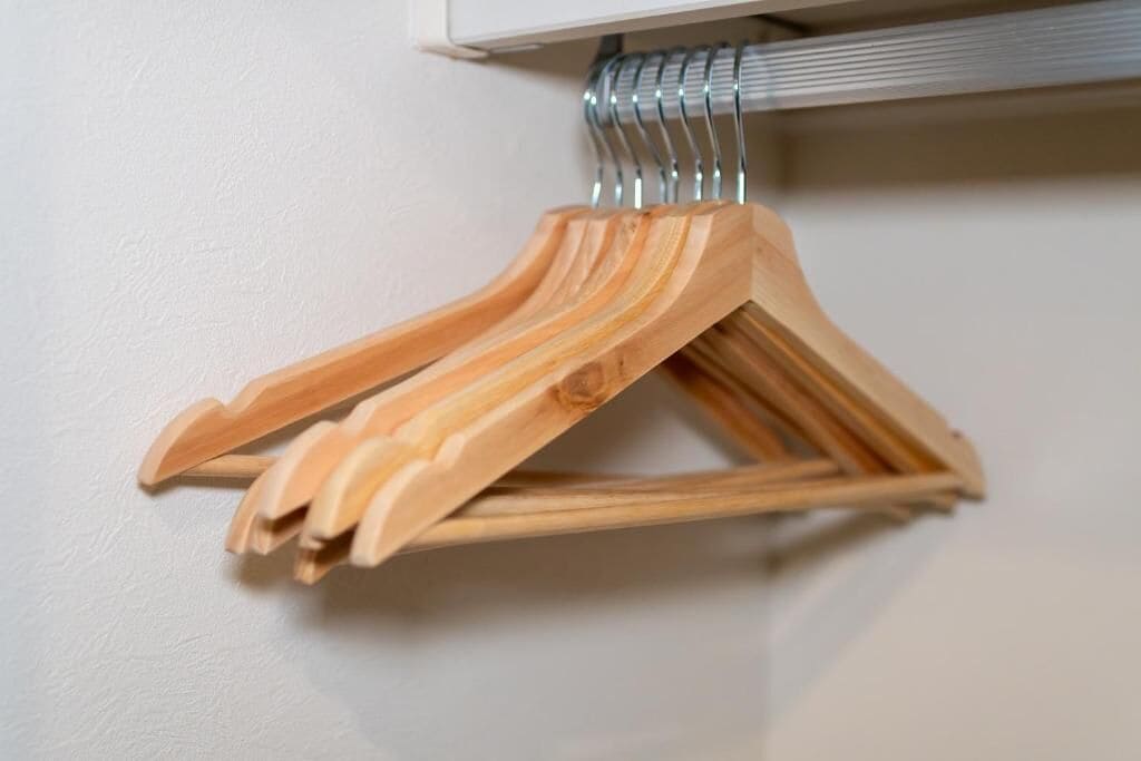 Ein Holzaufhänger mit Metallfeder an einer Wand.