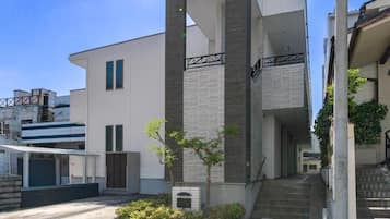 Un bâtiment moderne doté d’un toit plat, d’un petit arbre et d’un escalier menant à l’entrée.