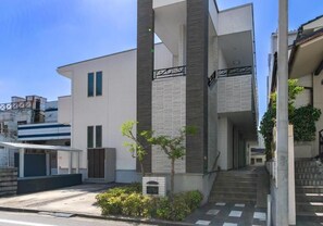 Un bâtiment moderne doté d’un toit plat, d’un petit arbre et d’un escalier menant à l’entrée.