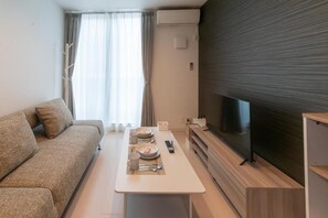 Una sala de estar moderna con un sofá, una mesa de comedor dispuesta con platos, cubiertos y un control remoto.