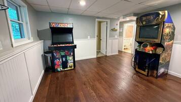 A room with two arcade machines, wooden flooring, and a door leading to another room.