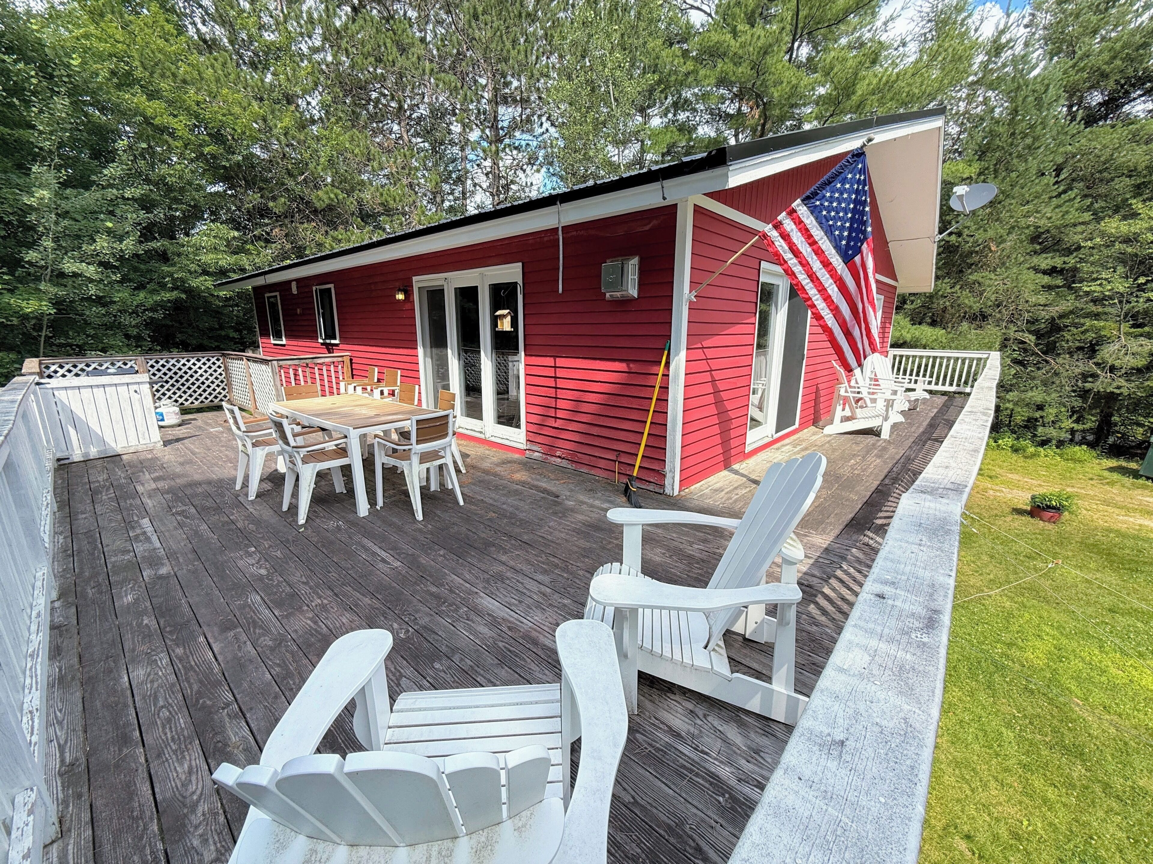 A red building with a deck, outdoor seating, and an American flag.