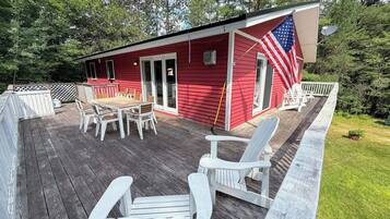 A red building with a deck, outdoor seating, and an American flag.