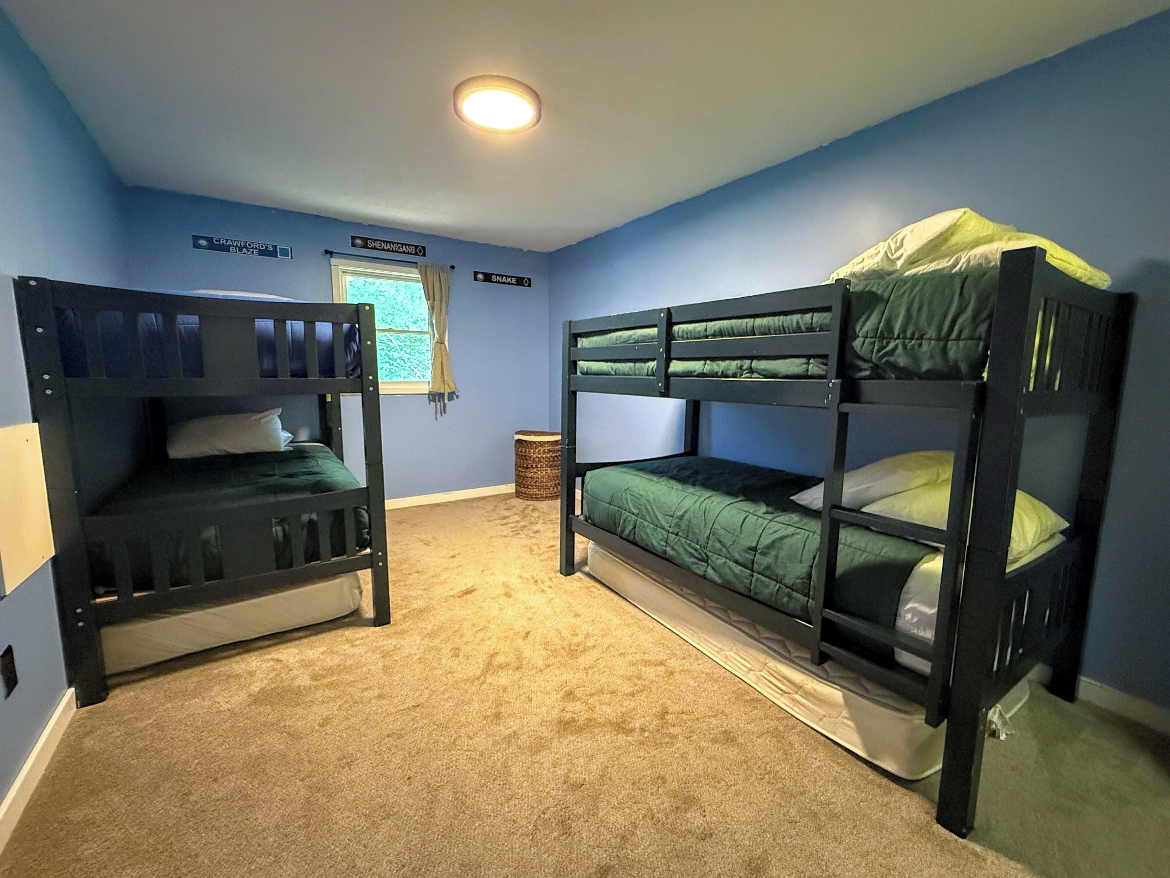 A room with two bunk beds, a window with curtains, and a ceiling light.