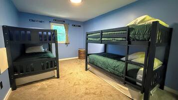 A room with two bunk beds, a window with curtains, and a ceiling light.