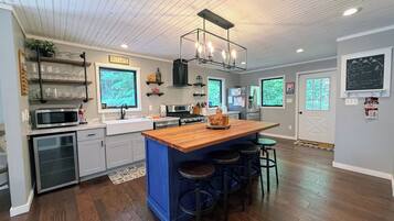 A modern kitchen with a central island, stainless steel appliances, and a wooden ceiling.