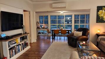 A living room with a flat-screen TV, bookshelves, a coffee table, and a sofa.