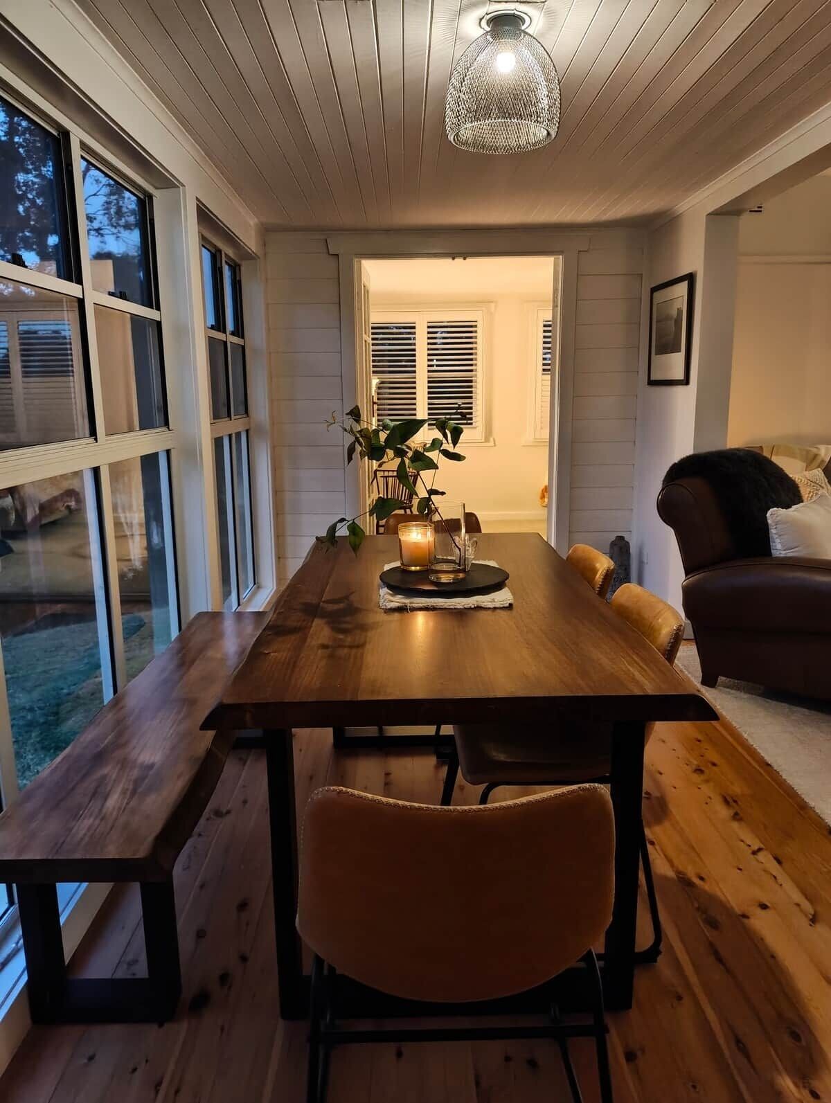 Een eethoek met een houten tafel, stoelen, een kaars en een hanglamp.