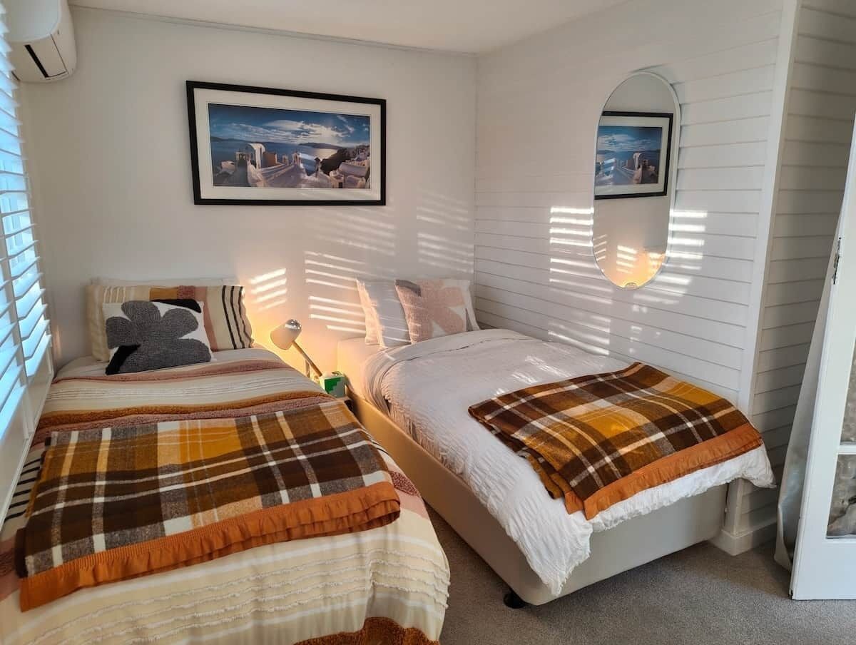 Een slaapkamer met twee bedden, een nachtkastje, een lamp en een lijst met een foto aan de muur.