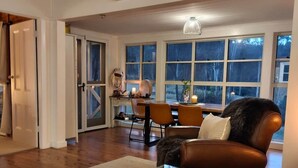 Ett vardagsrum med ett soffbord i glas, en lädersoffa och en matplats med stolar och ett bord.