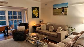A living room with a sofa, armchair, coffee table, and a painting on the wall.