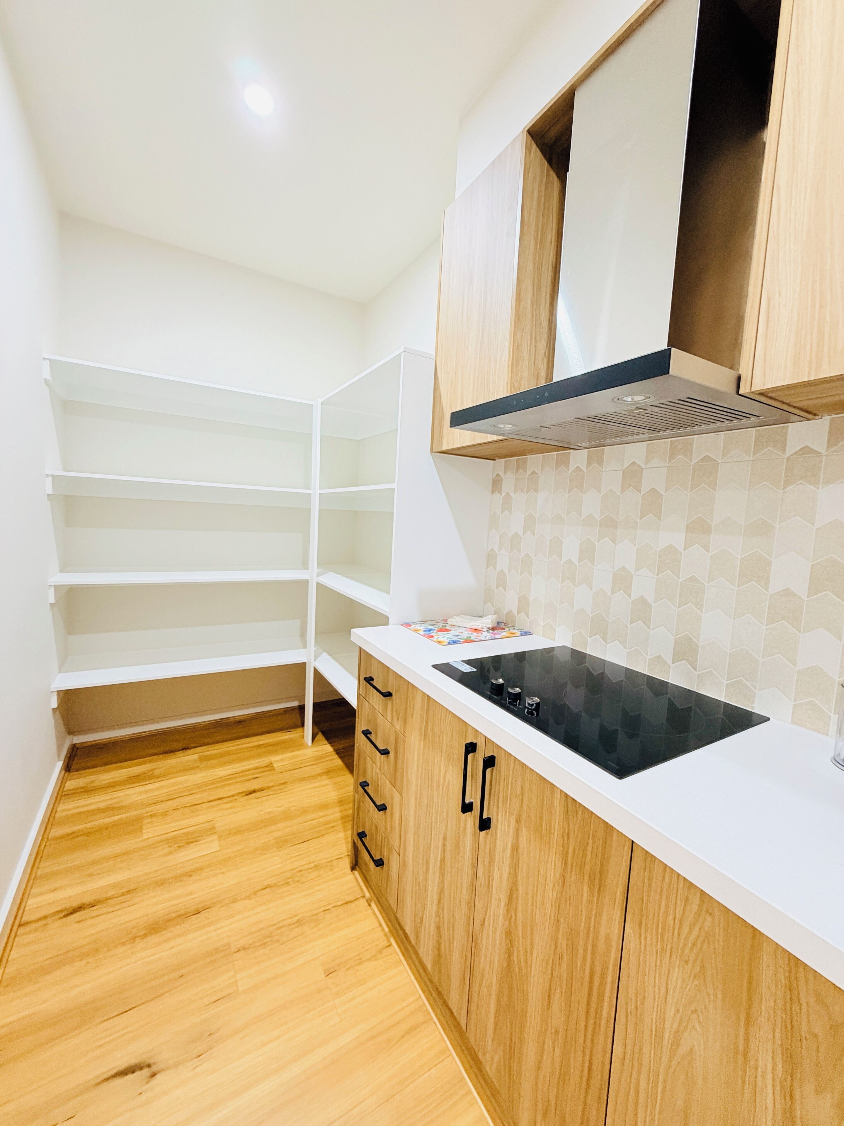 Une cuisine avec des meubles blancs, une cuisinière noire et un dosseret carrelé.