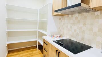 Une cuisine avec des meubles blancs, une cuisinière noire et un dosseret carrelé.