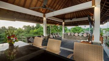 An outdoor covered seating area with wicker furniture, a table, and a ceiling fan.