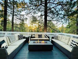An outdoor seating area with a fire feature, surrounded by tall trees. - Fantastic 3-bedroom house in delightful Big Bear Lake getaway (Big Bear Lake)