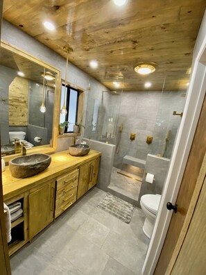 A modern bathroom with a wooden vanity, a large mirror, a stone sink, and a glass-enclosed shower area. - Fantastic 3-bedroom house in delightful Big Bear Lake getaway (Big Bear Lake)