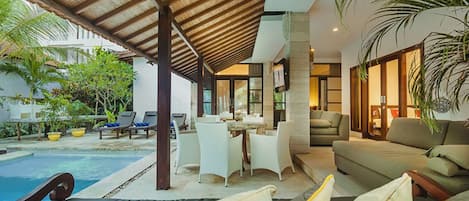 A poolside area with lounge chairs, a dining table, and a sofa.