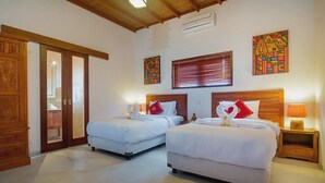 Habitación de hotel con dos camas, cabeceros de madera, una puerta corredera y obras de arte en las paredes.