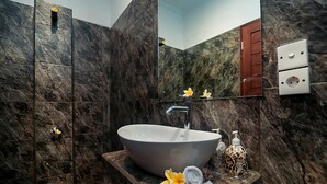 Un baño con un lavamanos grande de mármol, un espejo y un perchero para toallas.