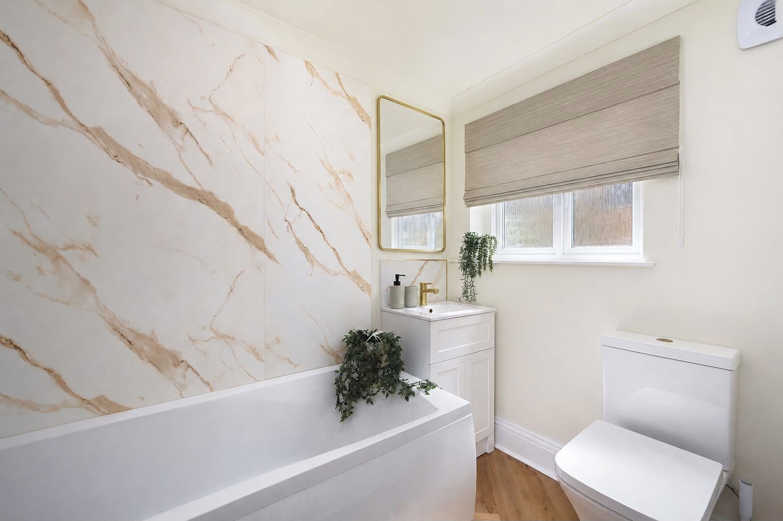 Un baño con pared de mármol, un lavamanos blanco, un inodoro y una ventana con persiana.