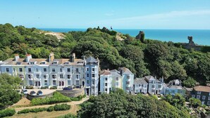 A coastal property with multiple buildings, a clear view of the sea, and lush greenery. - 1 Bed - Sleeps 2 - Near Beach - Parking (Hastings)