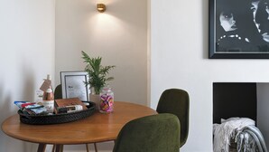 A dining area with a round wooden table, green upholstered chairs, a framed picture on the wall, and a potted plant. - 1 Bed - Sleeps 2 - Near Beach - Parking (Hastings)