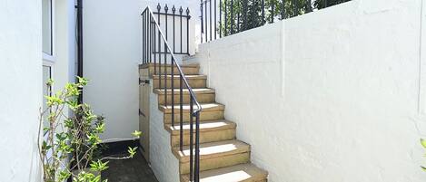 A concrete staircase with metal railings leading to a white wall.