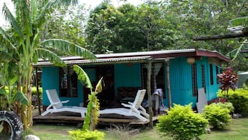 A small, single-story building with a porch and two white lounge chairs.