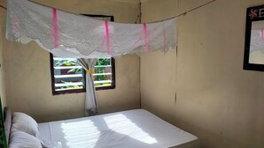 Une pièce avec un lit, une fenêtre avec un rideau et un cadre photo fixé au mur.