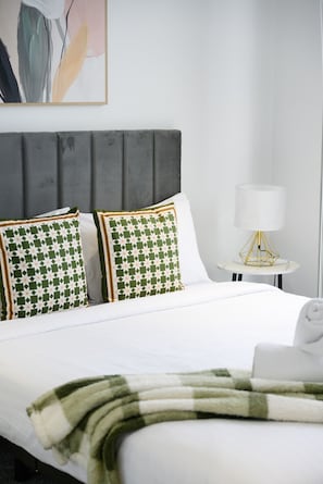 A neatly made bed with a white comforter and two pillows with a geometric pattern.
