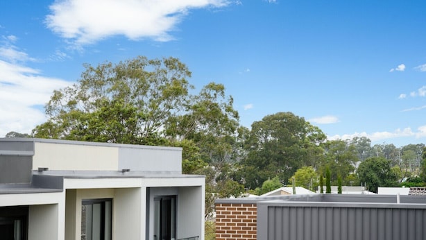 Un quartier résidentiel avec des bâtiments modernes, un ciel bleu dégagé et des arbres en arrière-plan.