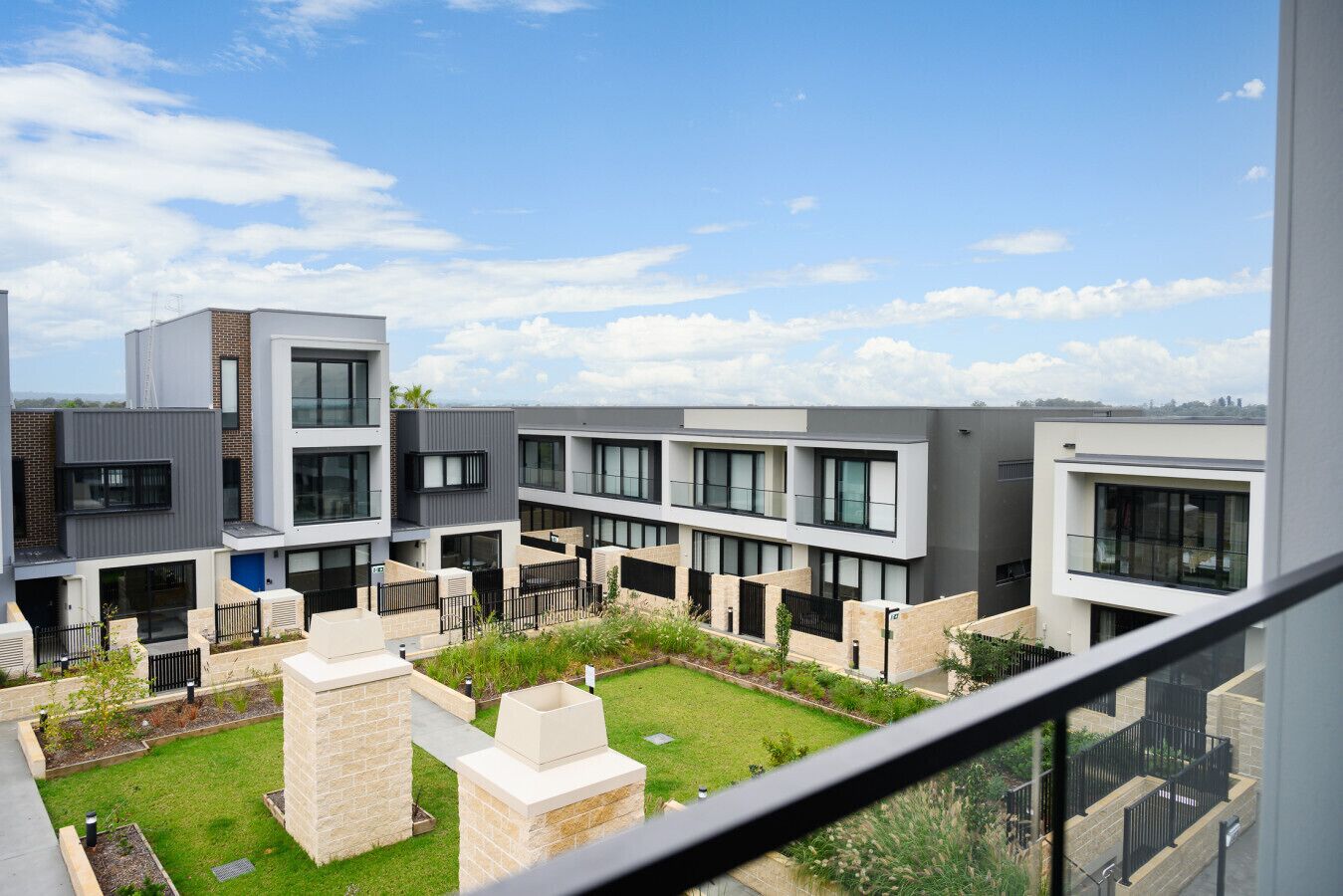 Um edifício residencial moderno com várias varandas, um pátio central e céu claro.