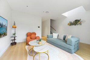 A modern living room with a sofa, a coffee table, and a unique orange chair.