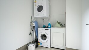 Une buanderie équipée d’un lave-linge, d’un sèche-linge et d’un seau à serpillière.