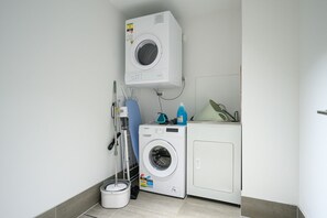 Une buanderie équipée d’un lave-linge, d’un sèche-linge et d’un seau à serpillière.
