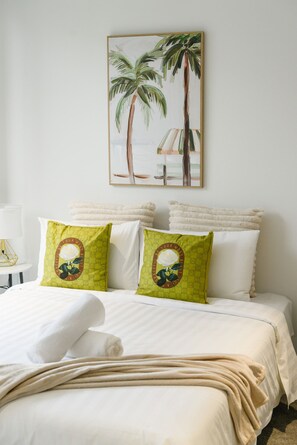 A hotel room with a bed, pillows, a painting of palm trees, and a lamp. - Brand New Family Home for 10 | Boxhill (Box Hill)