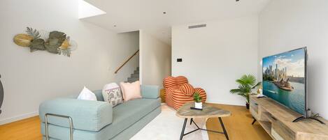 A modern living room with a sofa, a striped chair, a small table, and a painting on the wall.