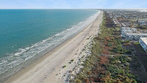 Luftaufnahme einer Küstenstadt mit Strand, Gebäuden und Grünflächen.