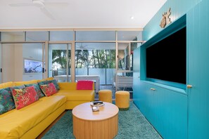 A modern living room with a yellow sofa, a round coffee table, and a large teal cabinet. - The Fishbowl - 1Bed-1Bath-1Car-Pool (Bulimba)
