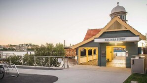 Ein Gebäude mit einem Schild, auf dem 'BULIMBA FERRY' steht, und einer Anlegestelle, die sich in ein Gewässer erstreckt.