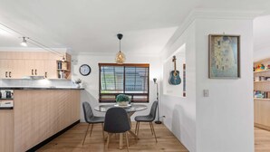 Una cocina moderna con comedor, armarios de madera y un reloj en la pared.
