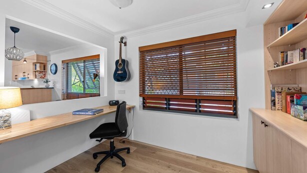 Un espacio de oficina moderno con un escritorio, una silla, una estantería y una guitarra.