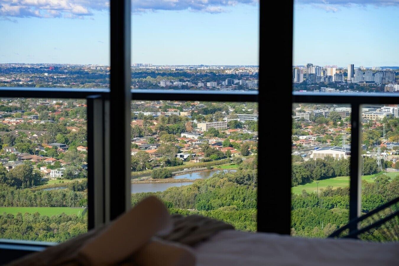 A room with a large window overlooking a cityscape with buildings and greenery.