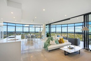 Ein modernes Interieur mit Essbereich, einer Couch und großen Fenstern mit Blick auf die Stadt.