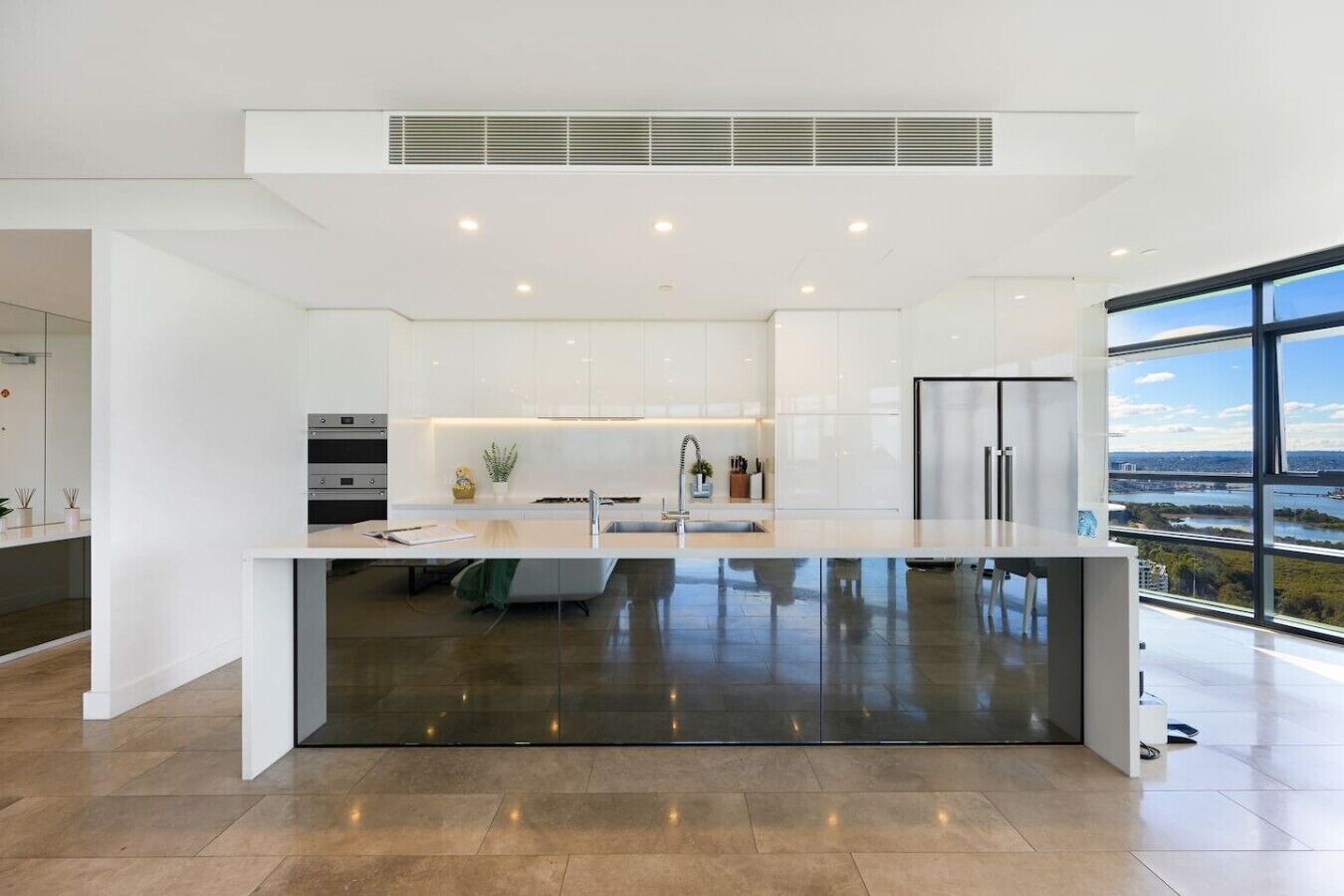 Una cocina moderna con una isla central, electrodomésticos integrados y un amplio ventanal con vistas a la ciudad.