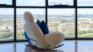 Un fauteuil à bascule moderne offrant une vue sur la ville grâce à de grandes fenêtres.