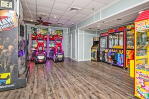 Eine Indoor-Spielhalle mit verschiedenen Spielautomaten, darunter Rennspiele und Greifklauen-Spiele, sowie eine Reihe von Spielkabinen.