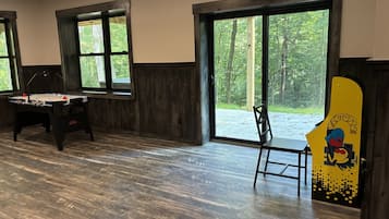 A room with a foosball table, a chair, and a large window with a view of trees.